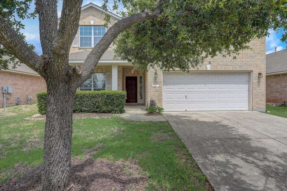 a front view of a house with a yard and a tree