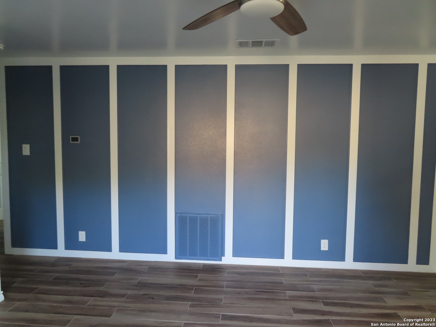 an empty room with wooden floor closet and windows