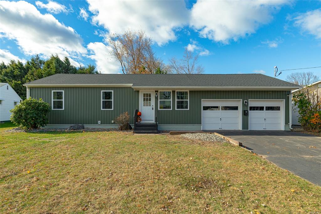 Ranch-style house featuring a garage and a front lawn