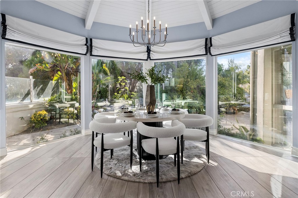 a dining room with wooden floor a chandelier a glass table and chairs