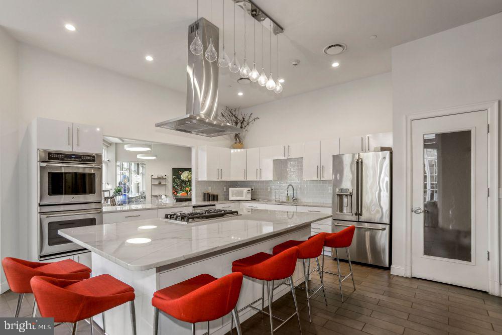 a kitchen with stainless steel appliances granite countertop a sink refrigerator dining table and chairs