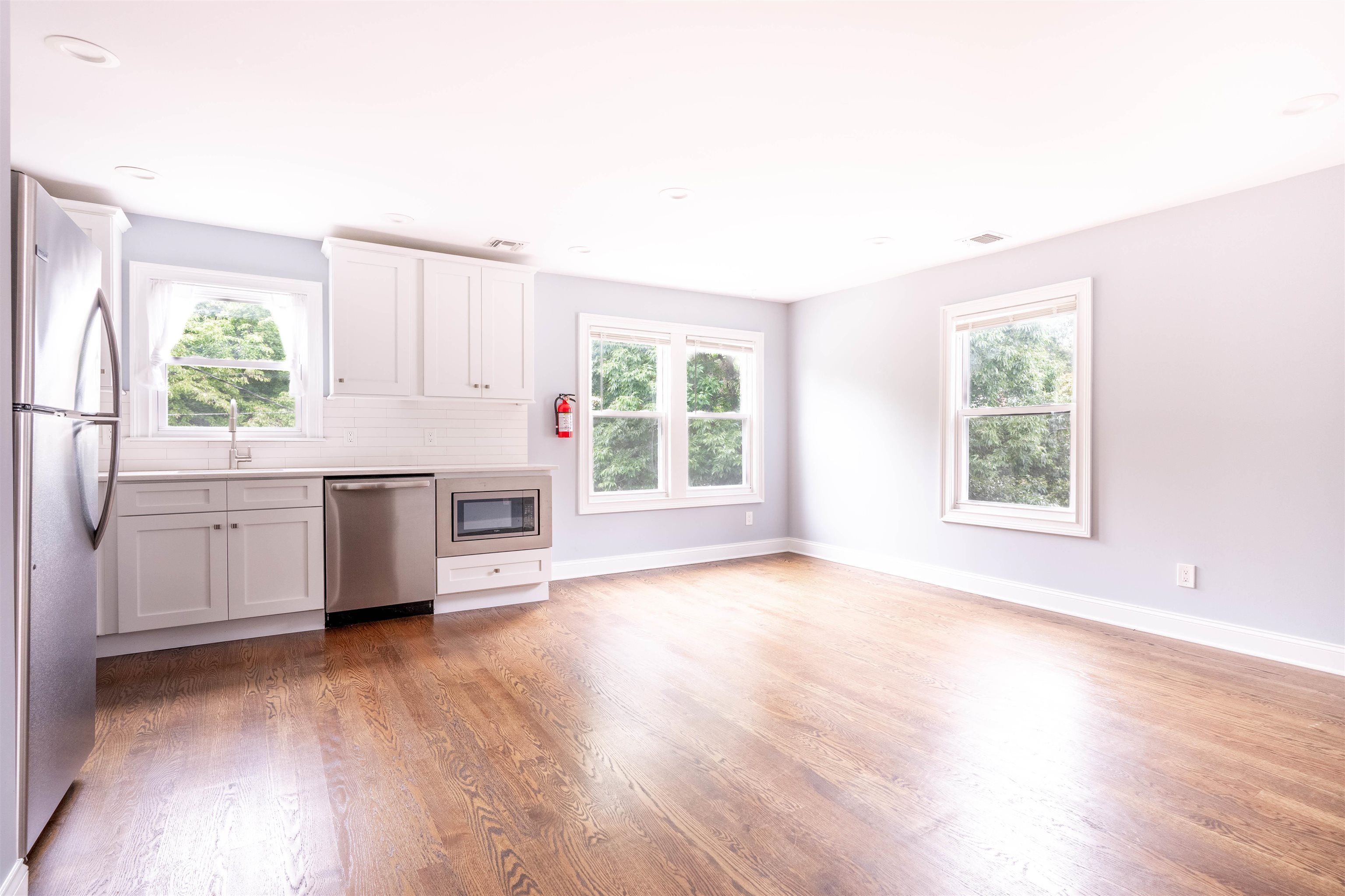 a view of a kitchen with a fridge wooden floor and a window