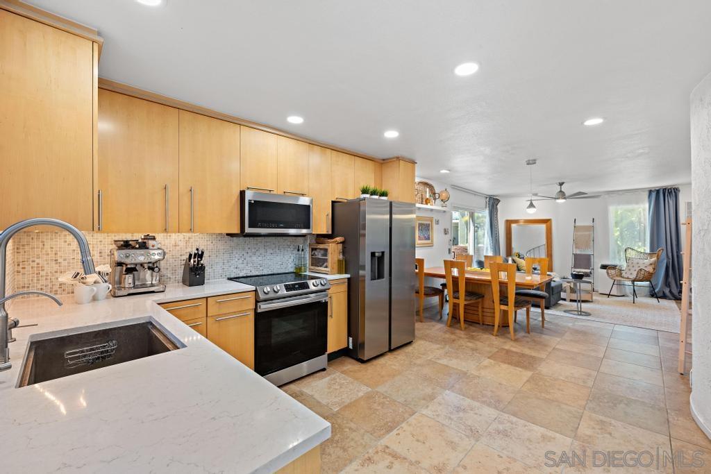 a kitchen with stainless steel appliances granite countertop a stove top oven a sink a dining table and chairs