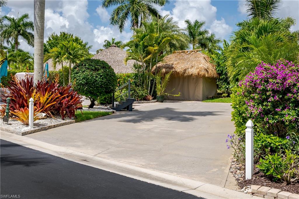 a backyard of a house with flower plants and palm trees