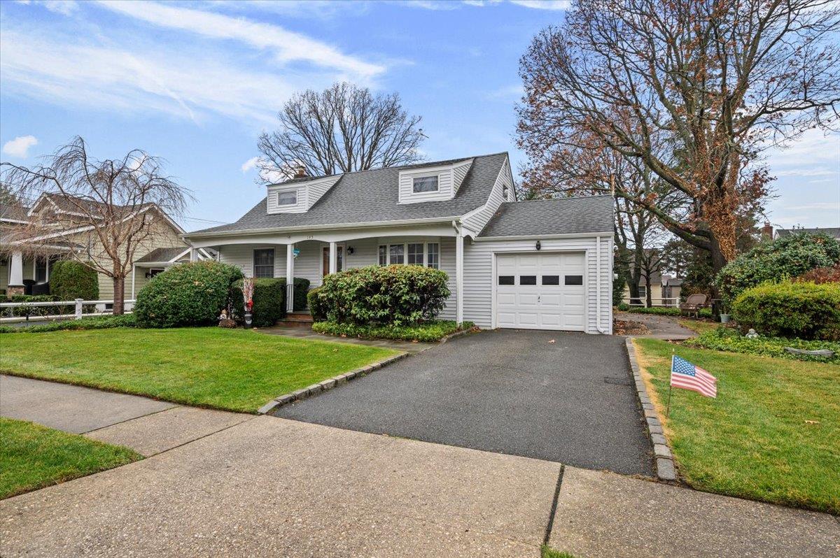 Cape cod house featuring a front lawn and a garage