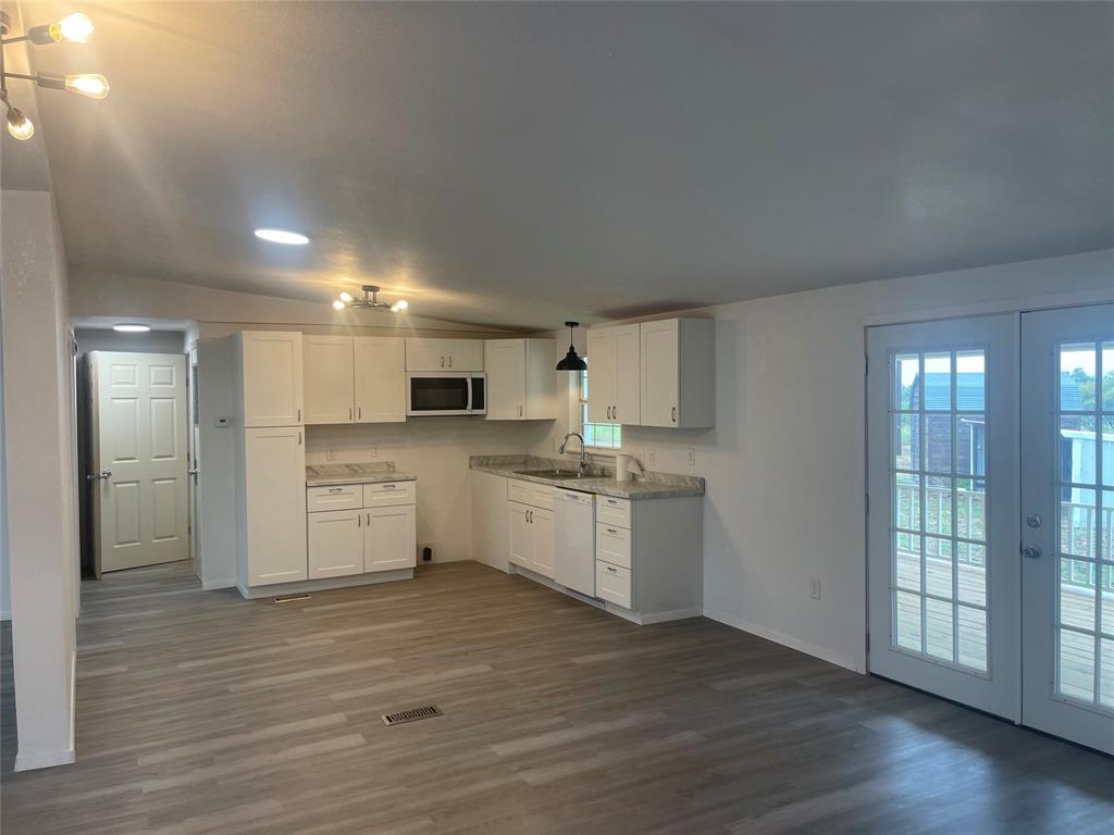 a large white kitchen with wooden floor