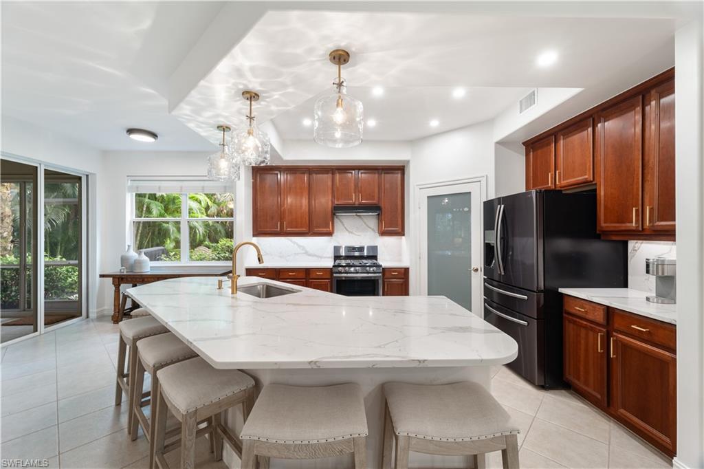 a kitchen with stainless steel appliances granite countertop a dining table chairs refrigerator and cabinets