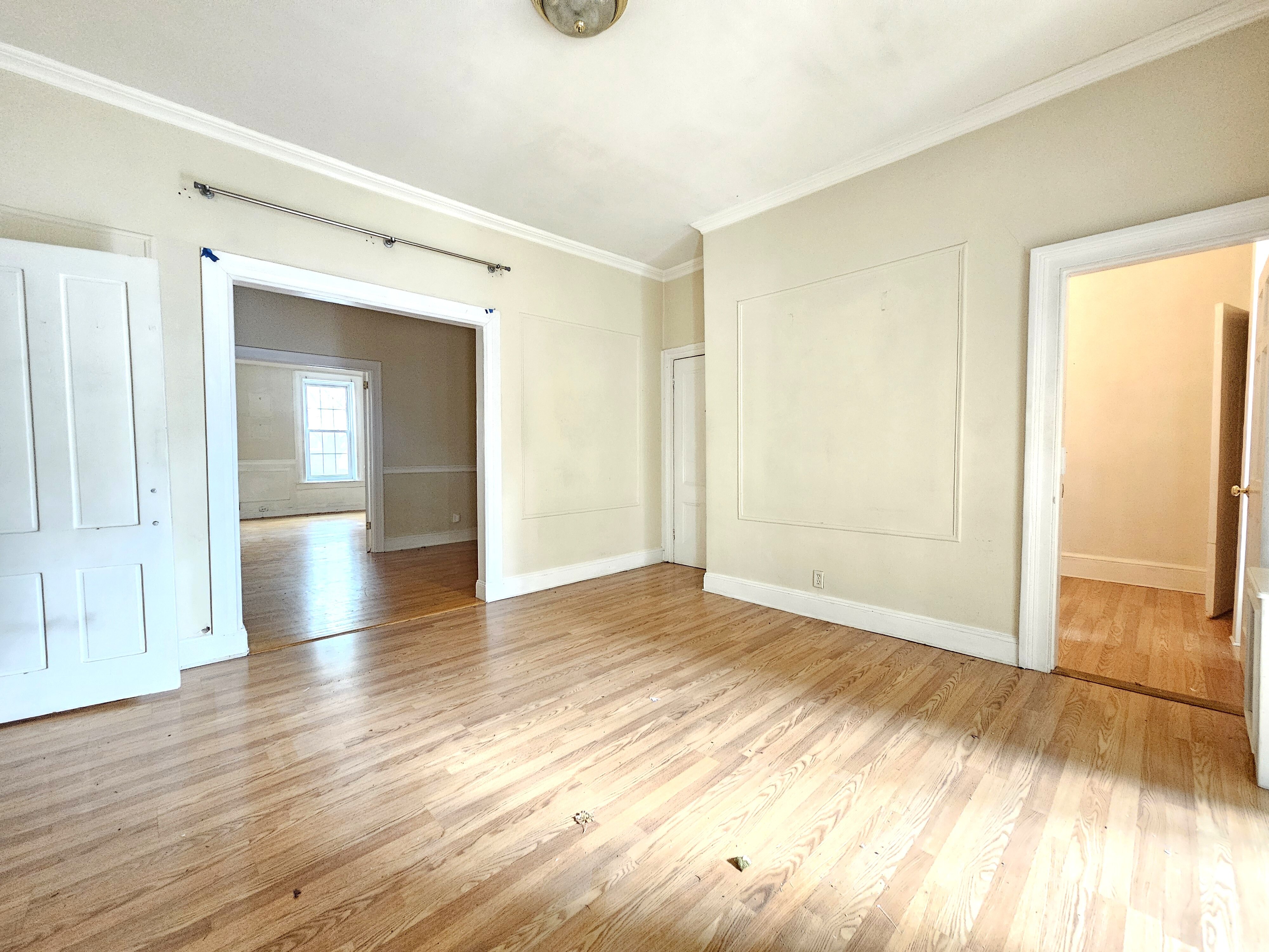 a view of empty room with wooden floor and fan