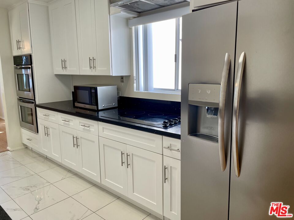 a kitchen with stainless steel appliances granite countertop white cabinets and a refrigerator