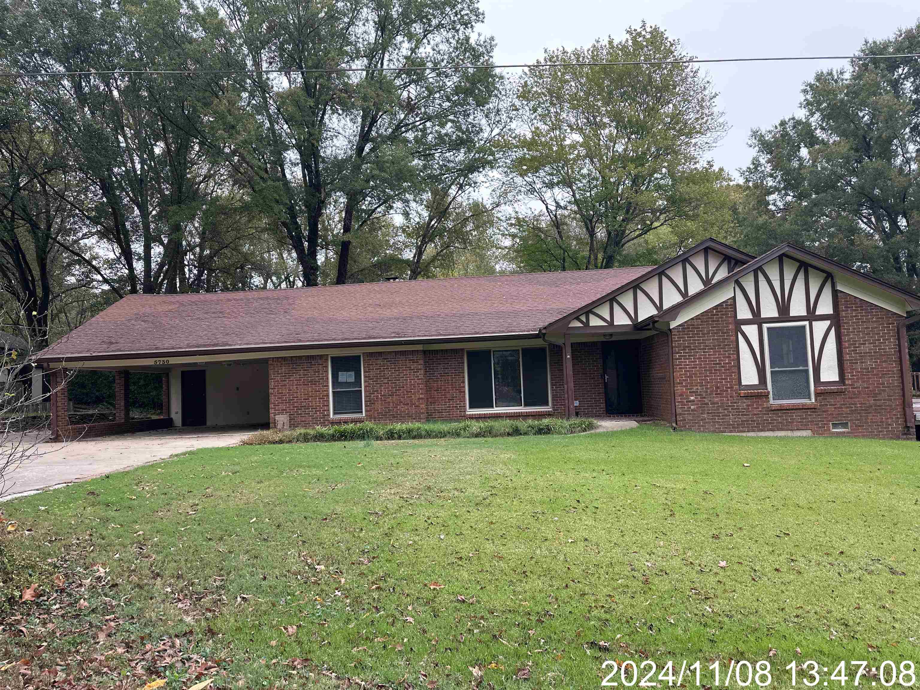 View of front facade featuring a front lawn and a carport