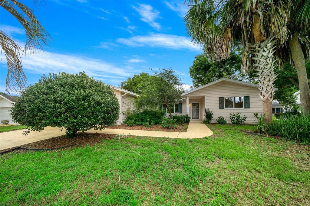 a view of a house with a yard and palm trees