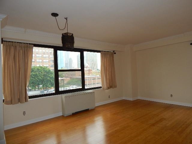 a view of an empty room with a window and wooden floor