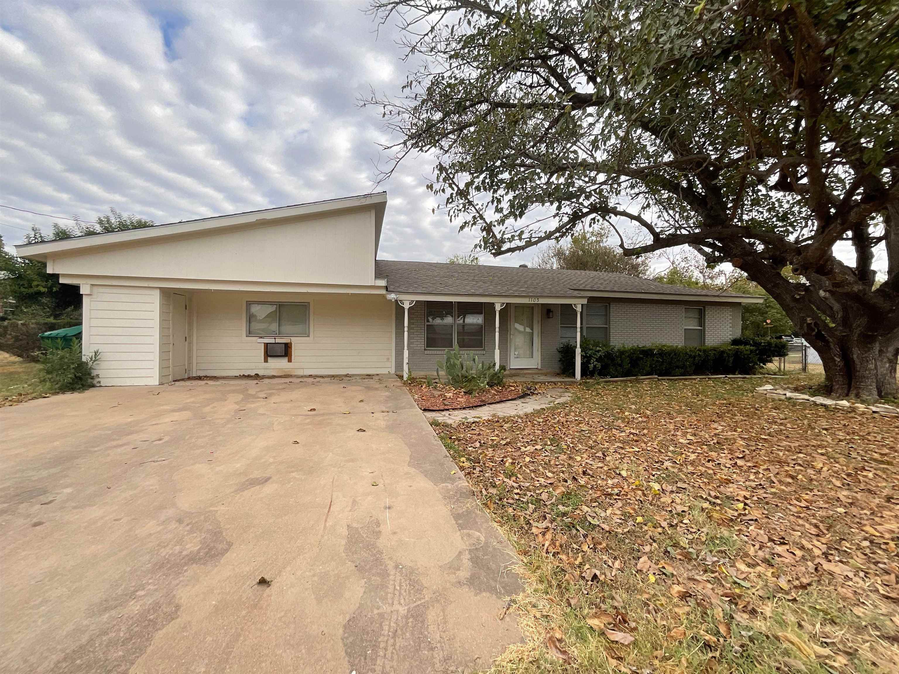 a view of a house with a yard and large tree