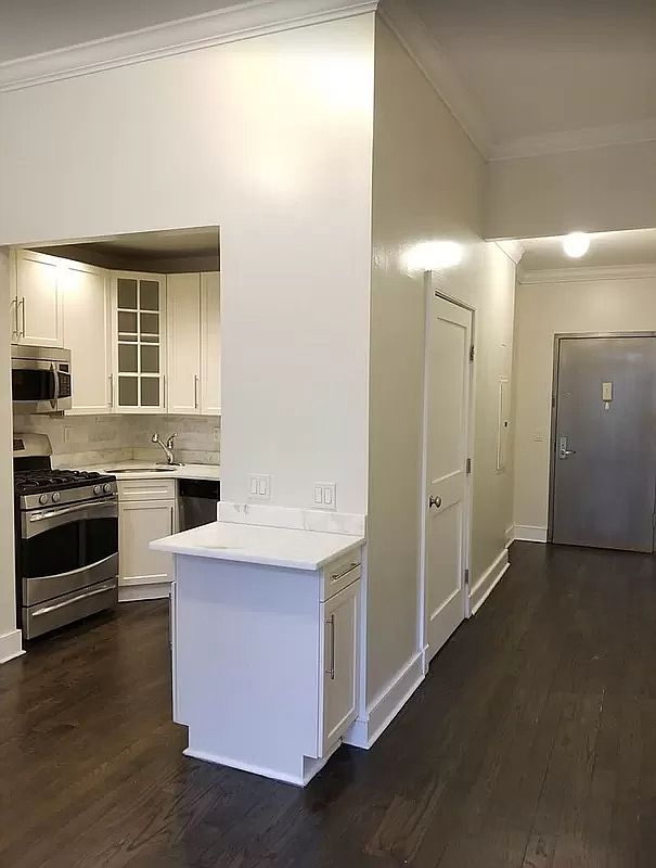 a kitchen with stainless steel appliances a stove and white cabinets