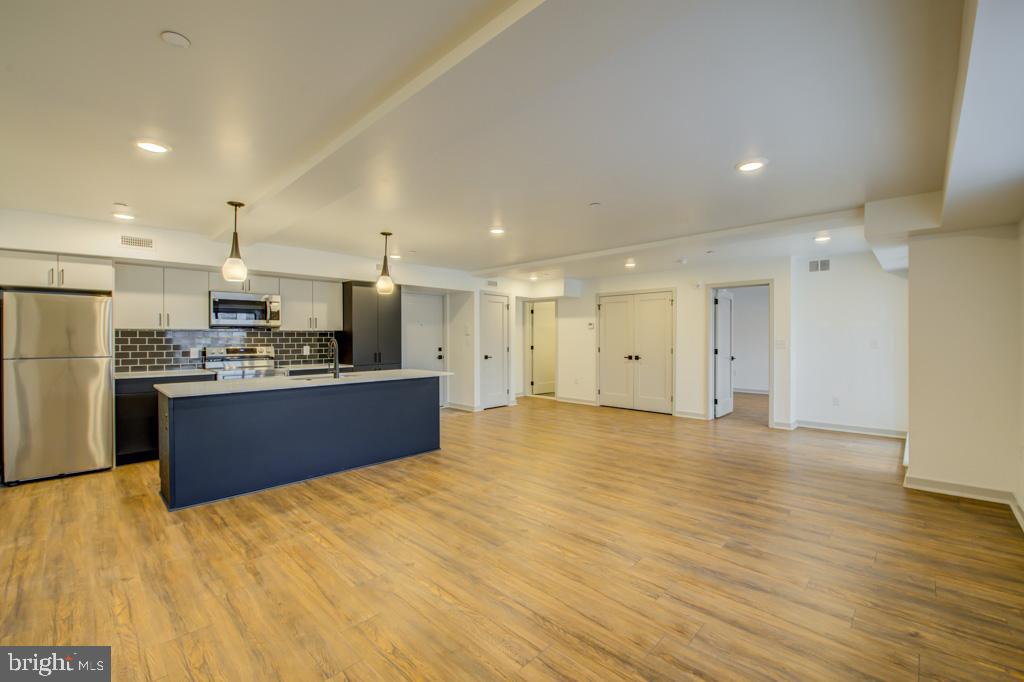 a large kitchen with stainless steel appliances kitchen island a large counter top and a refrigerator