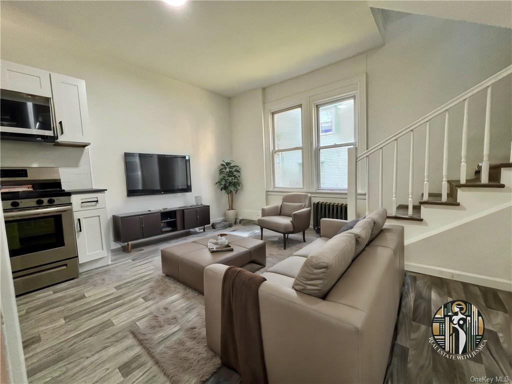 Living room with light wood-type flooring and radiator heating unit