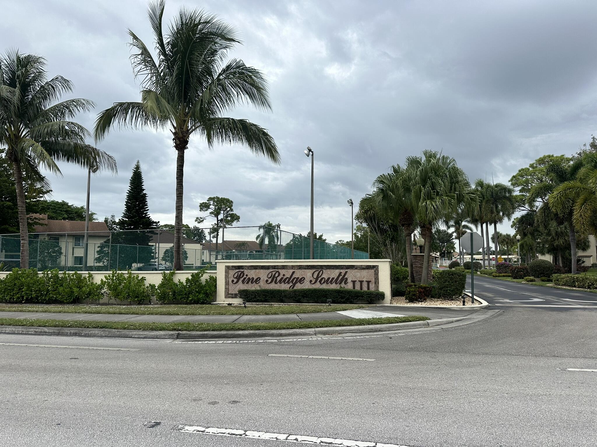 a front view of multi story residential apartment building with yard and sign board