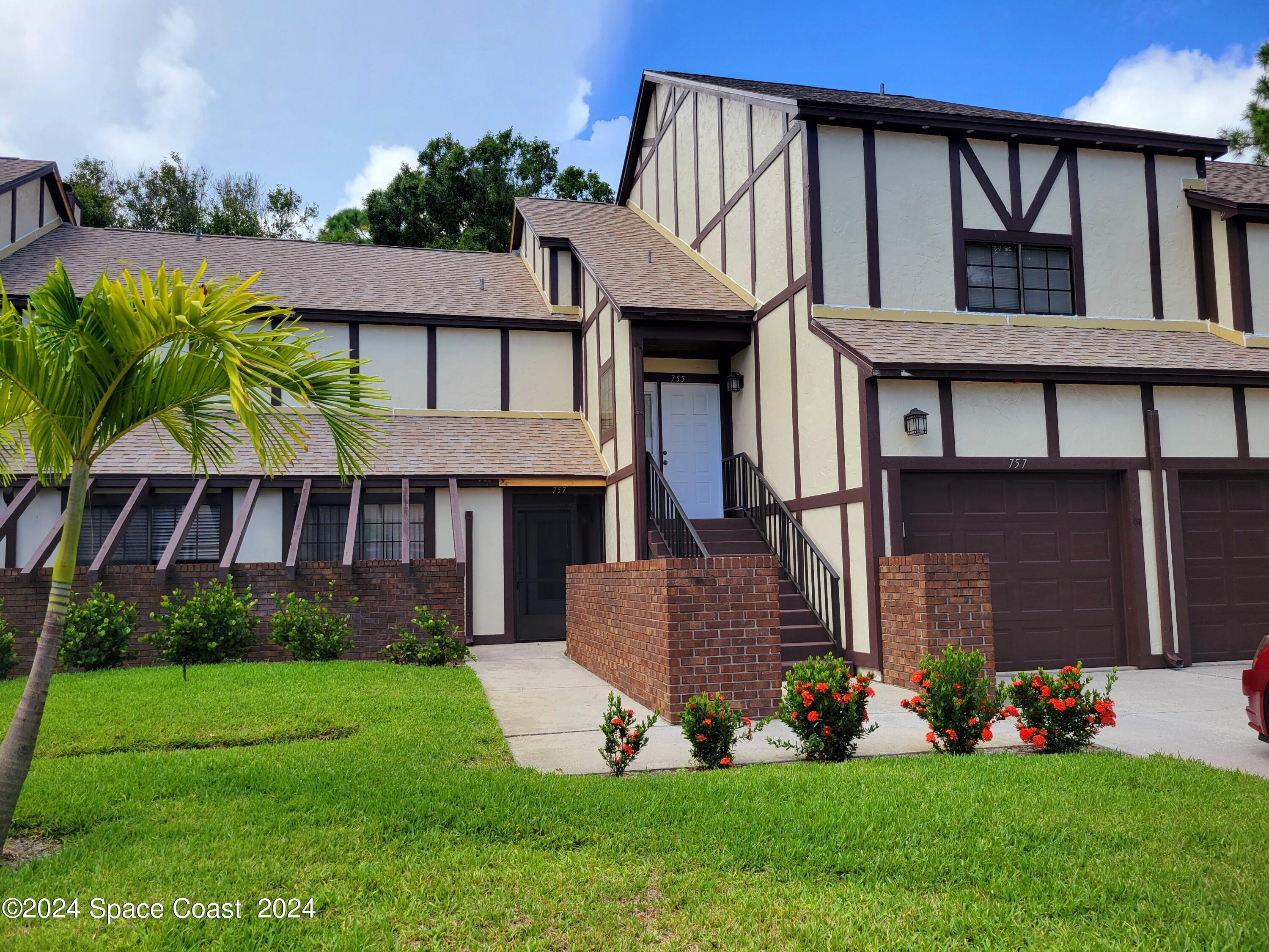 a front view of a house with a yard and potted plants