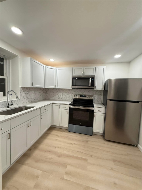 a kitchen with granite countertop white cabinets and stainless steel appliances