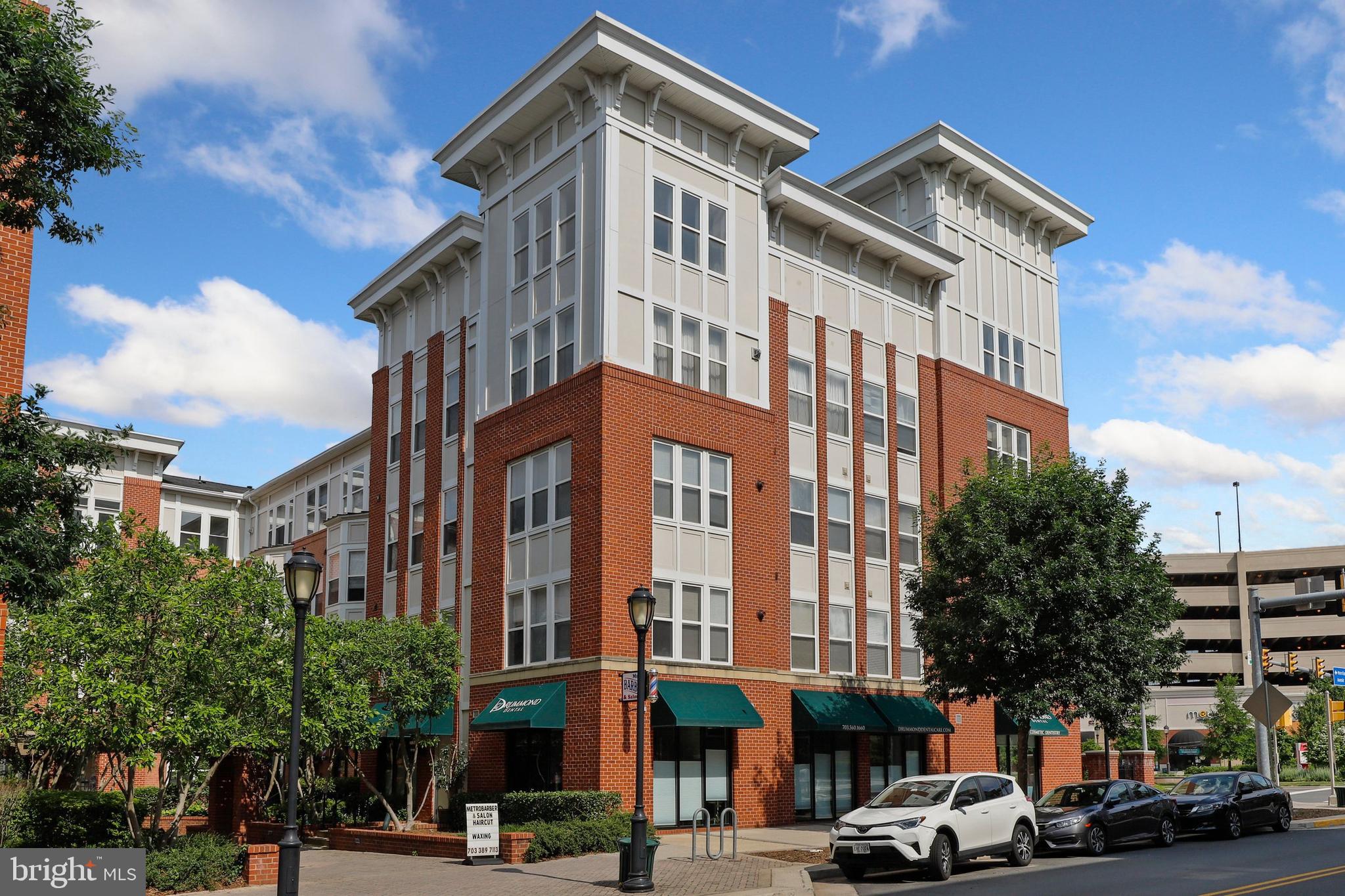 a front view of a building with lot of cars and trees