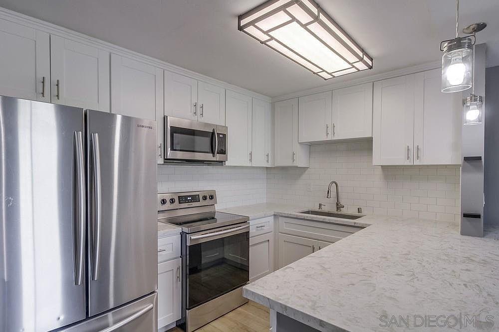 a kitchen with stainless steel appliances a refrigerator a stove a sink and white cabinets