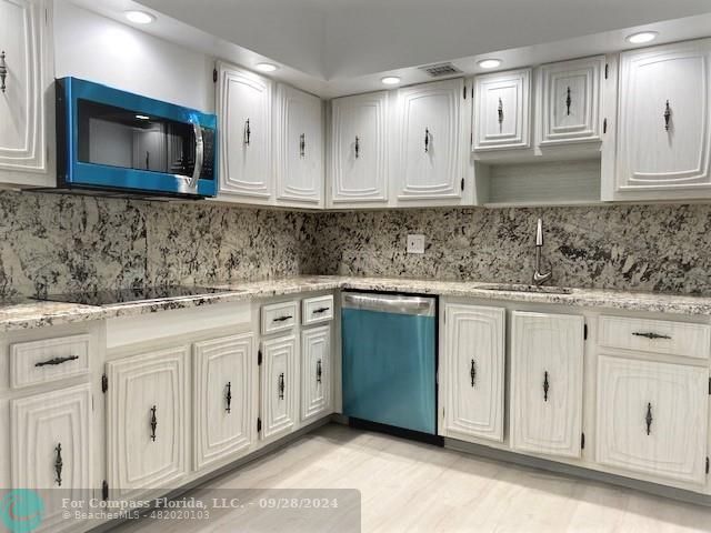 a kitchen with white cabinets granite counter tops and a sink