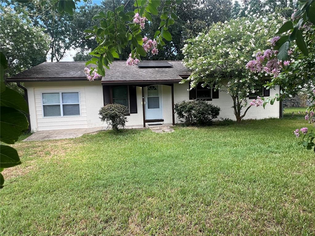 a front view of a house with a garden and trees