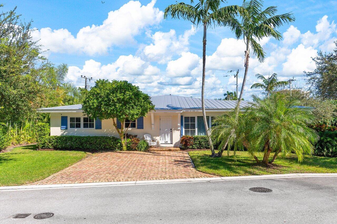 front view of house with a yard and palm trees