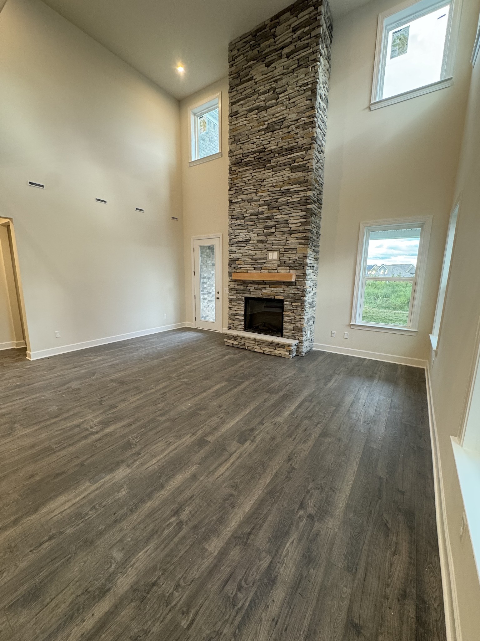 an empty room with wooden floor fireplace and windows