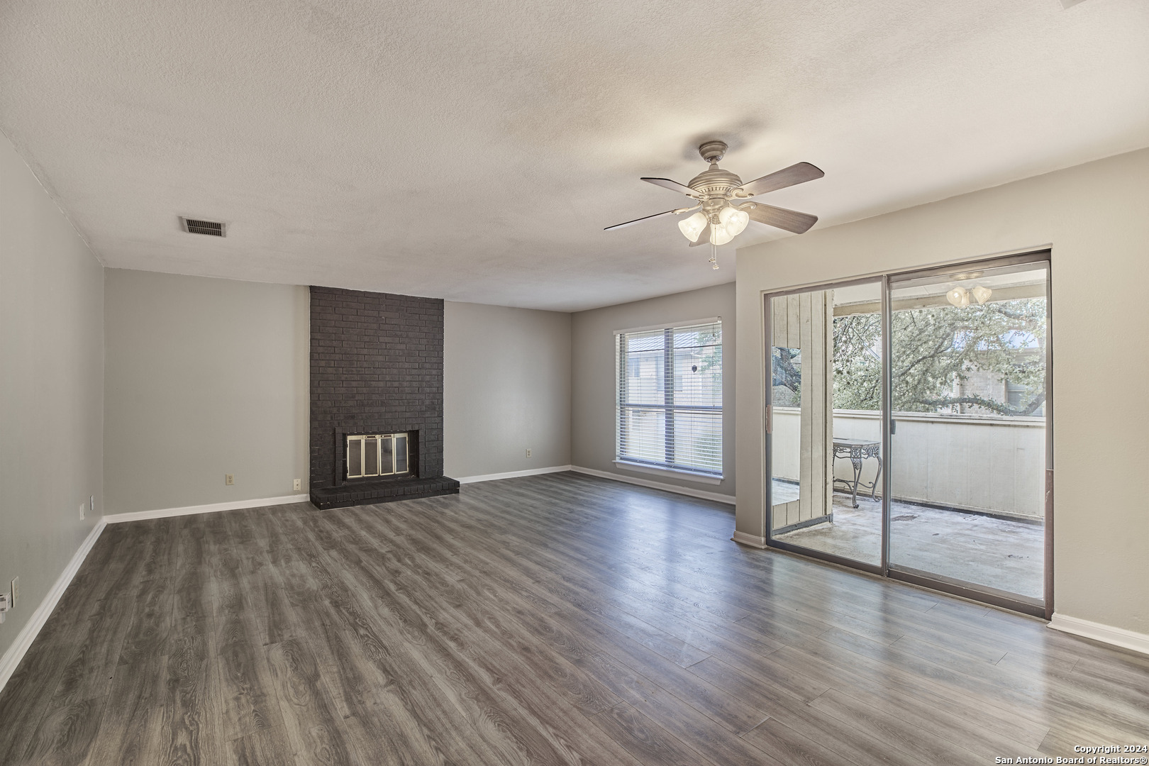 a view of an empty room with a window and wooden floor