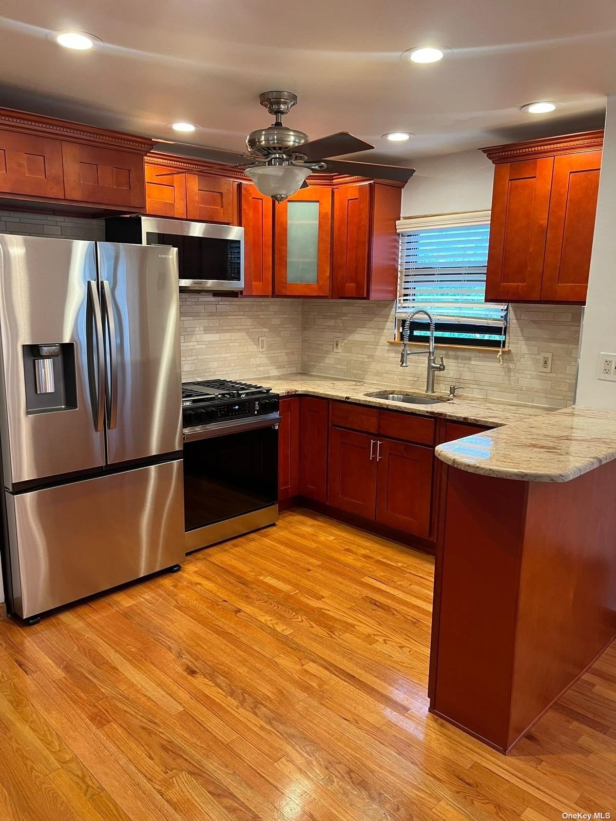 a kitchen with stainless steel appliances granite countertop a sink a stove and a refrigerator