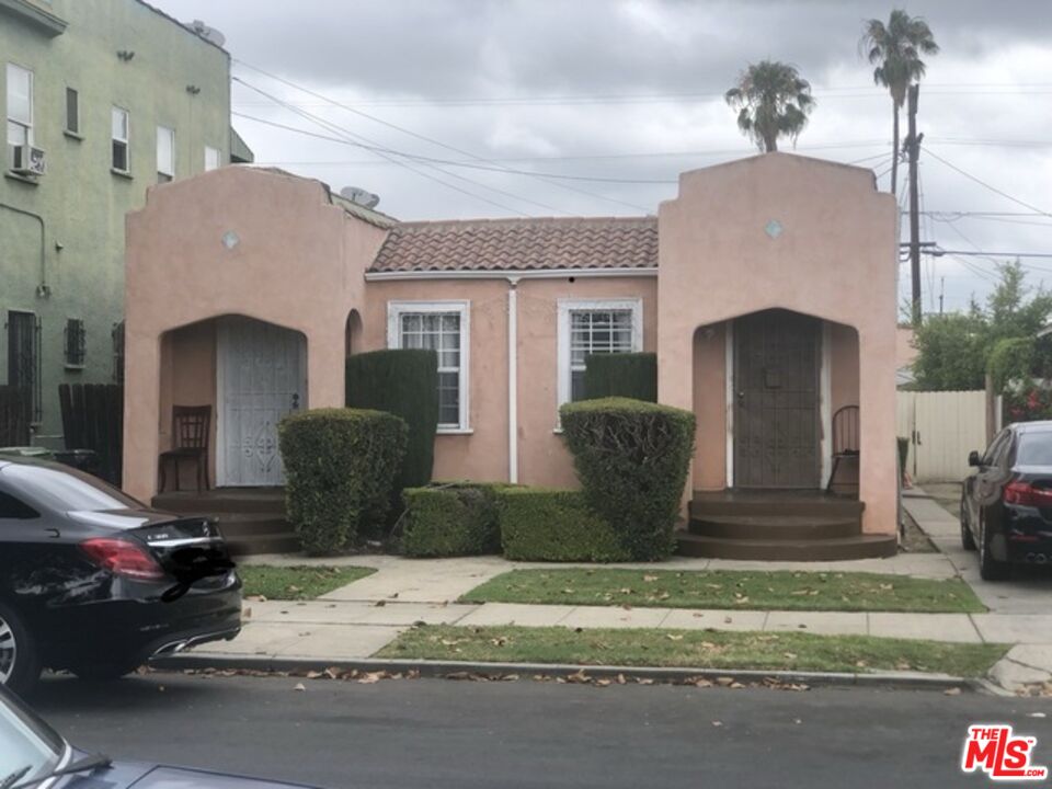 a view of a house with a cars park side of road