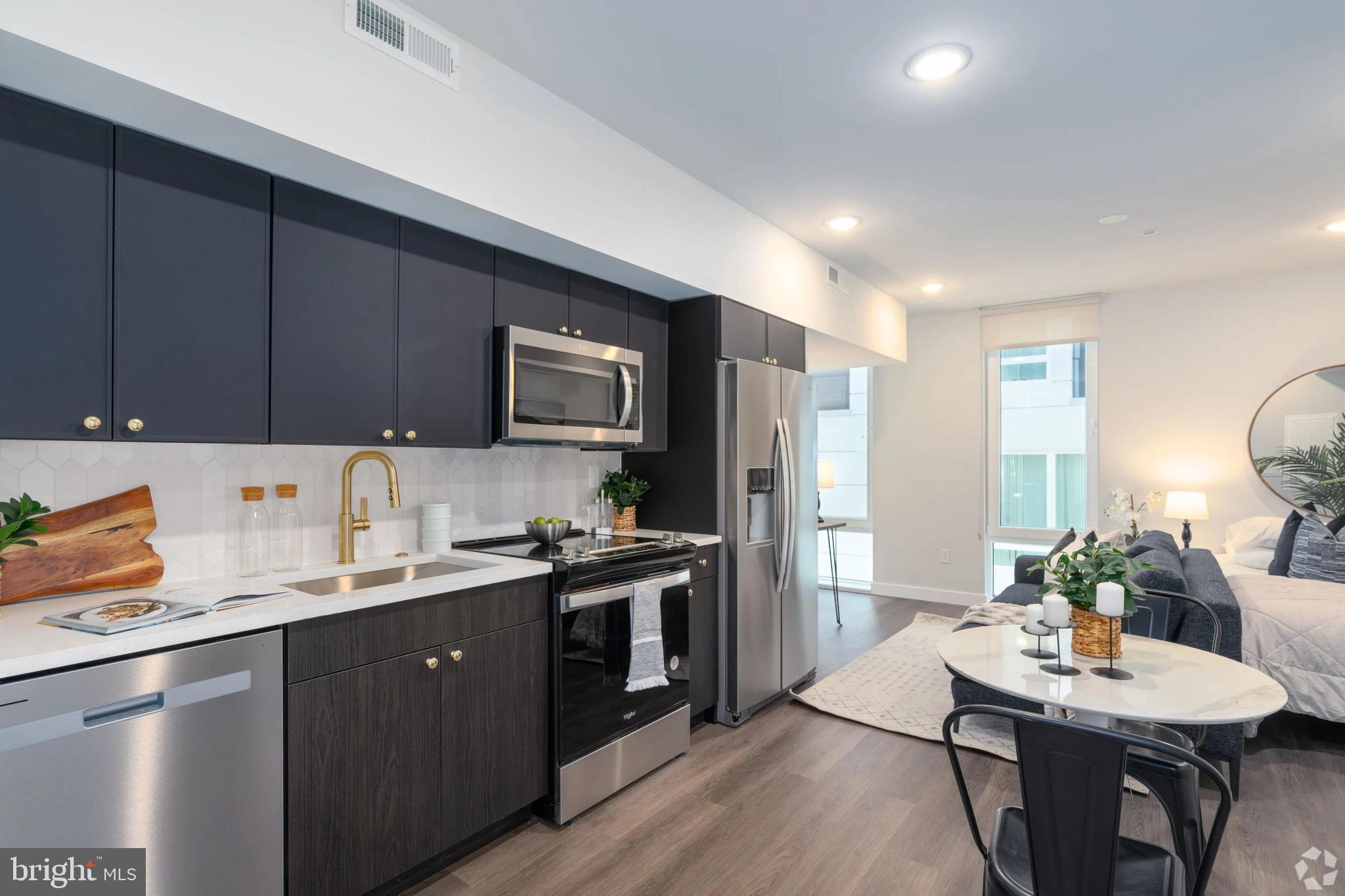 a kitchen with a sink a stove a refrigerator cabinets and a dining table