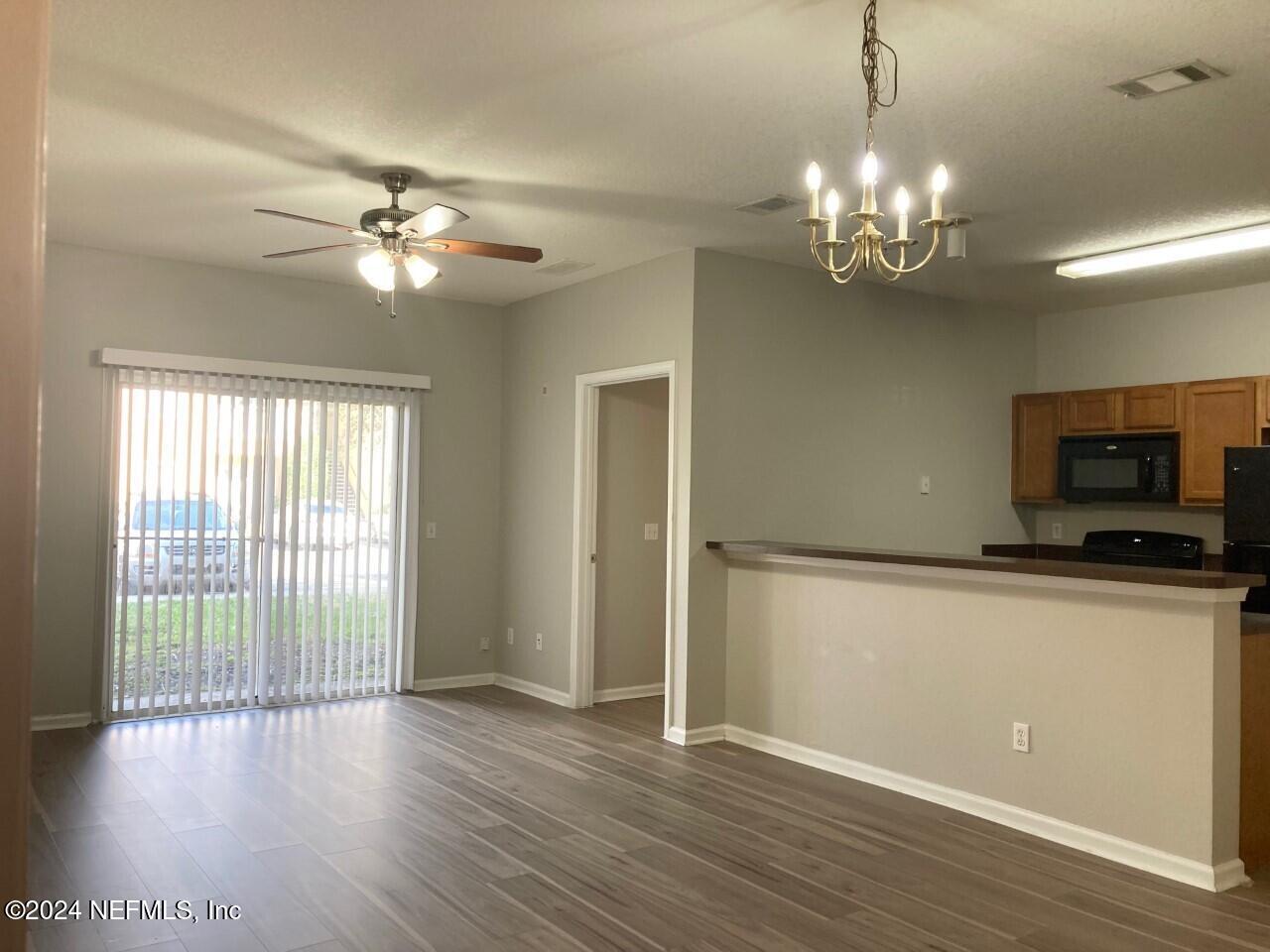 a view of a livingroom with a chandelier fan and wooden floor