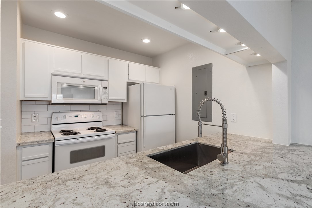 a kitchen with granite countertop a refrigerator stove and sink