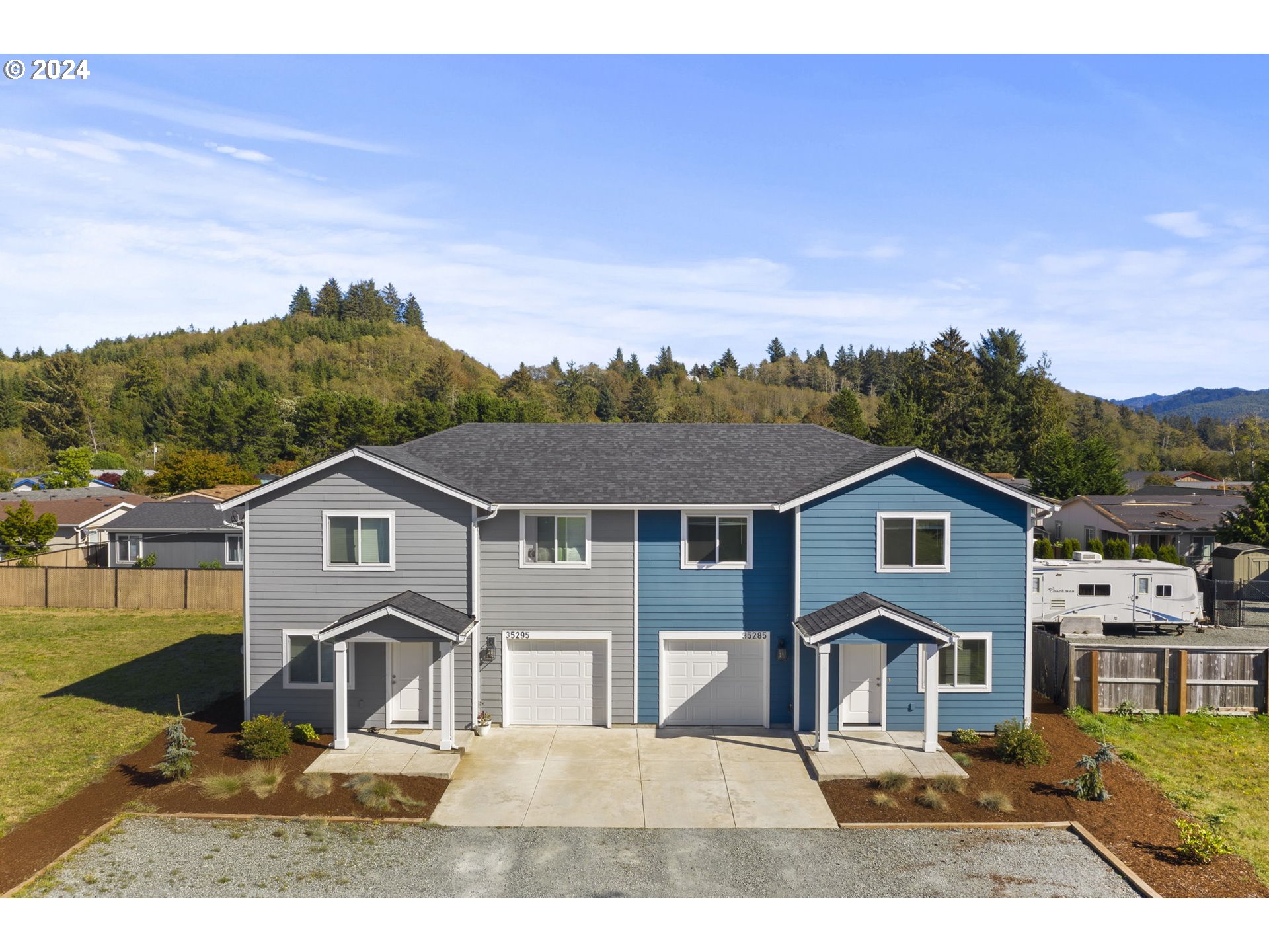 an aerial view of residential houses with outdoor space and trees