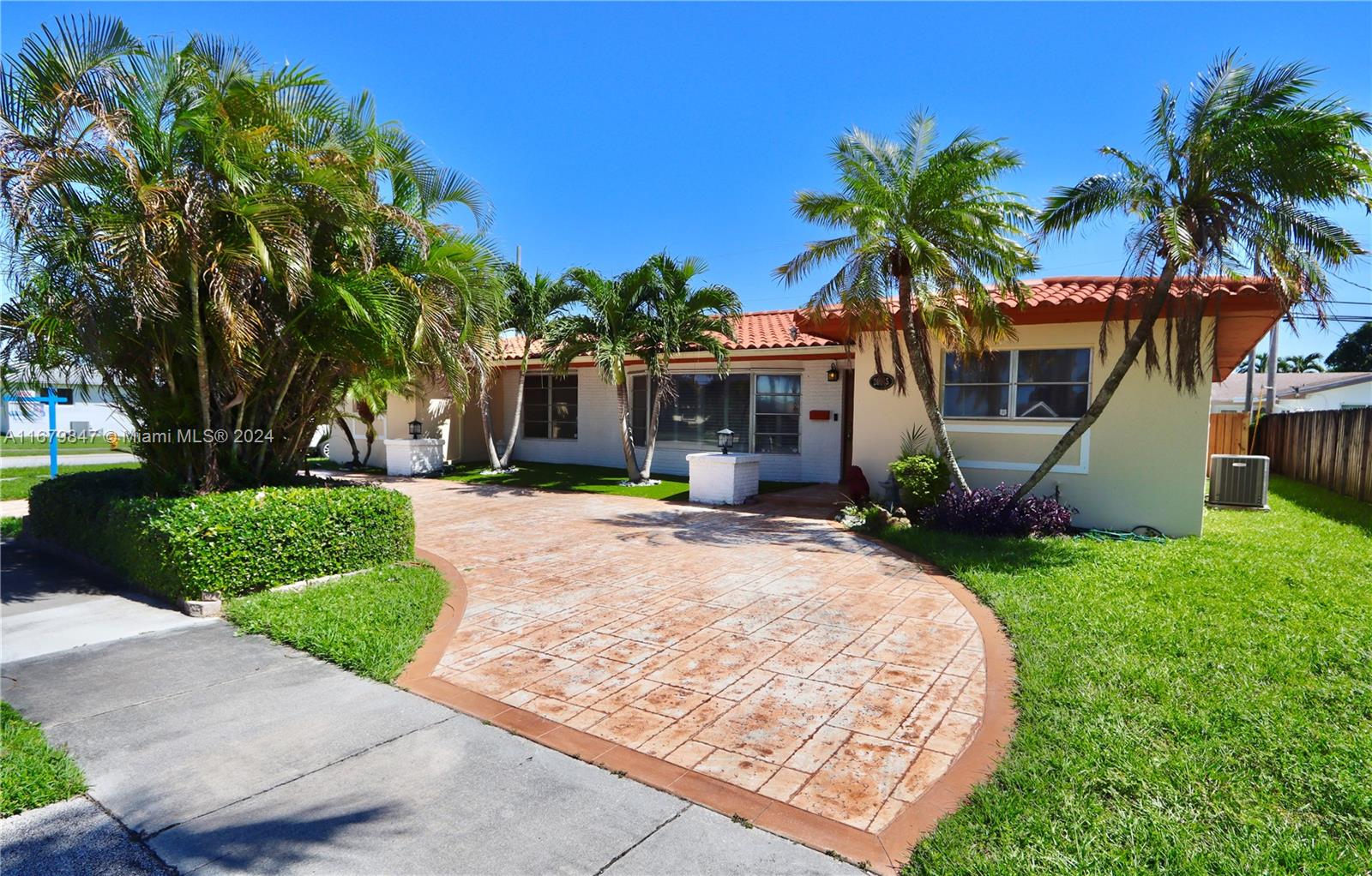 front view of house with a yard and palm trees