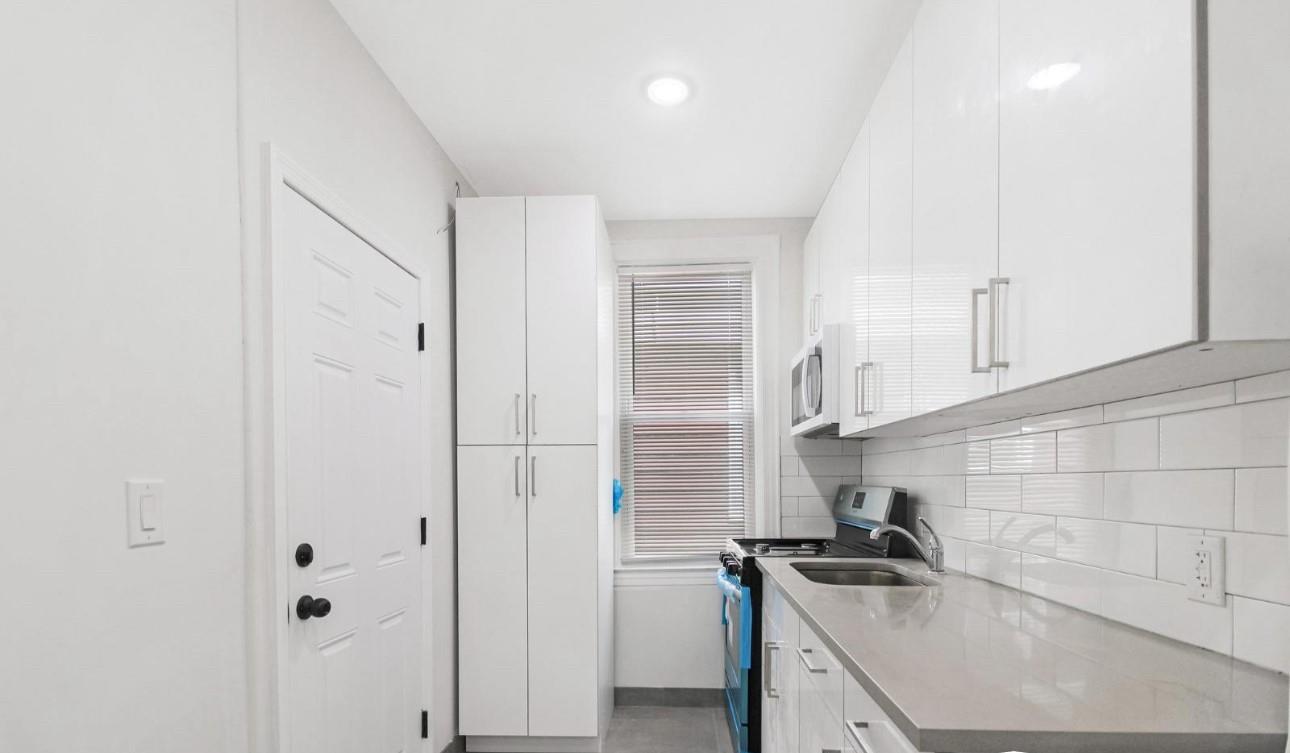 Kitchen featuring backsplash, white cabinetry, and stainless steel electric stove