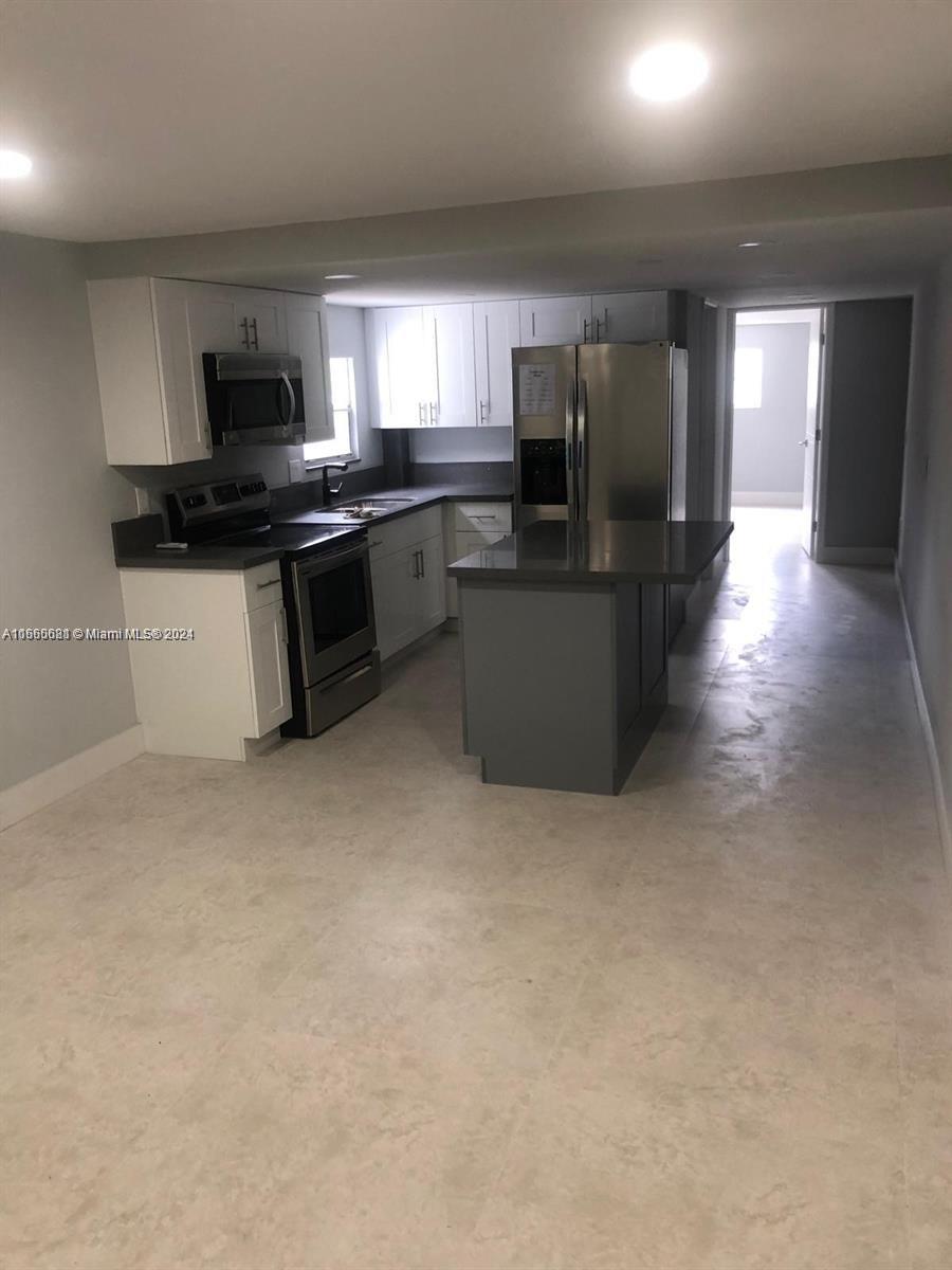 a kitchen with stainless steel appliances kitchen island granite countertop a stove a sink a refrigerator and a microwave