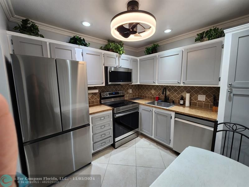 a kitchen with stainless steel appliances granite countertop a refrigerator a stove a sink and a microwave