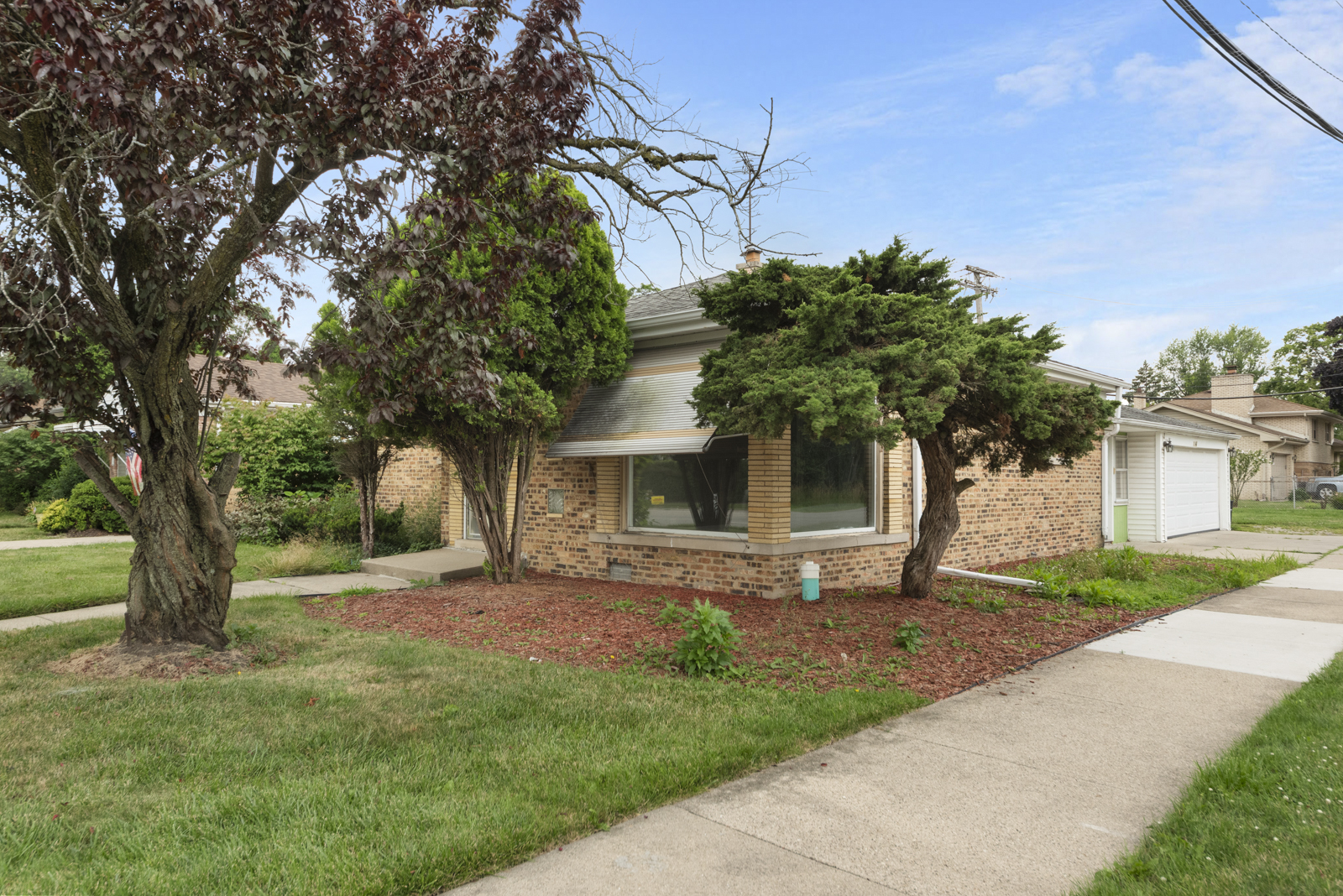 a front view of a house with a garden and trees