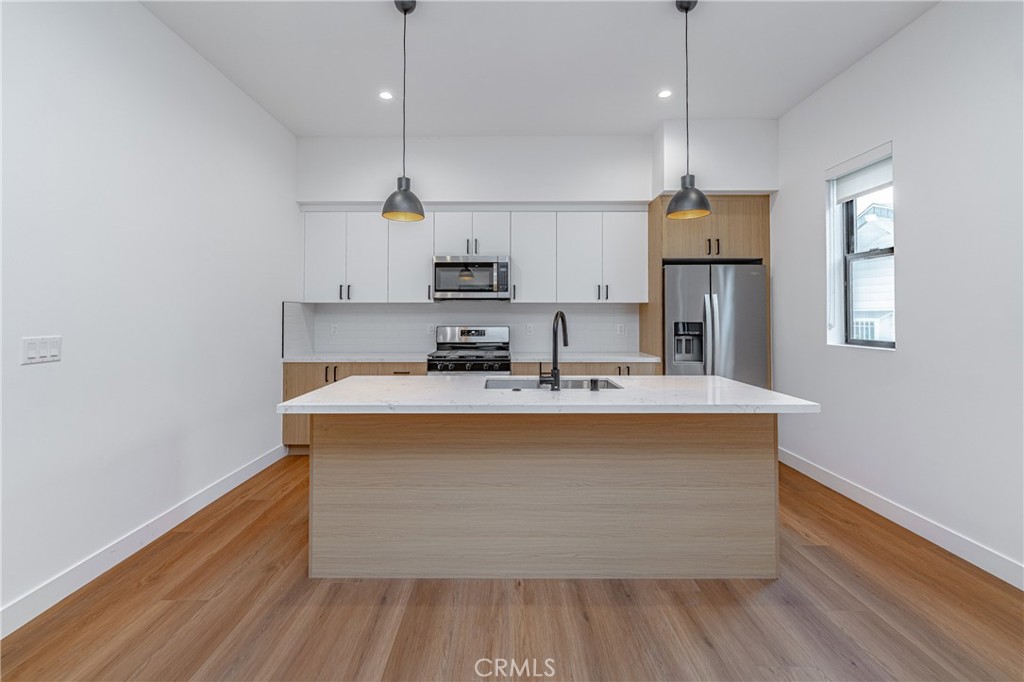 a view wooden floor with kitchen island stainless steel appliances wooden floor and window