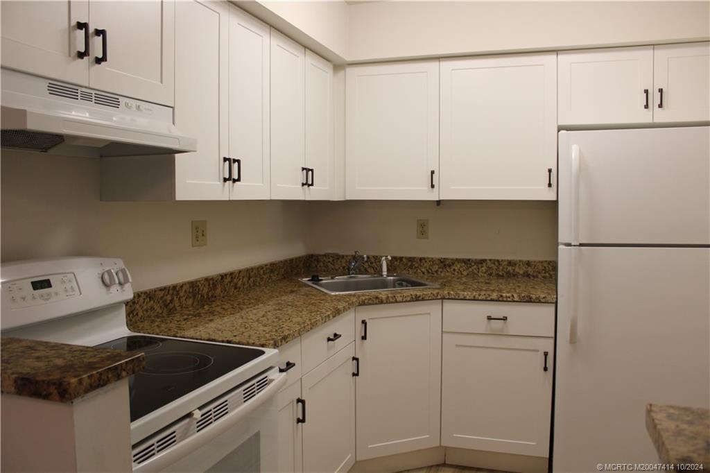 a kitchen with granite countertop white cabinets and white appliances