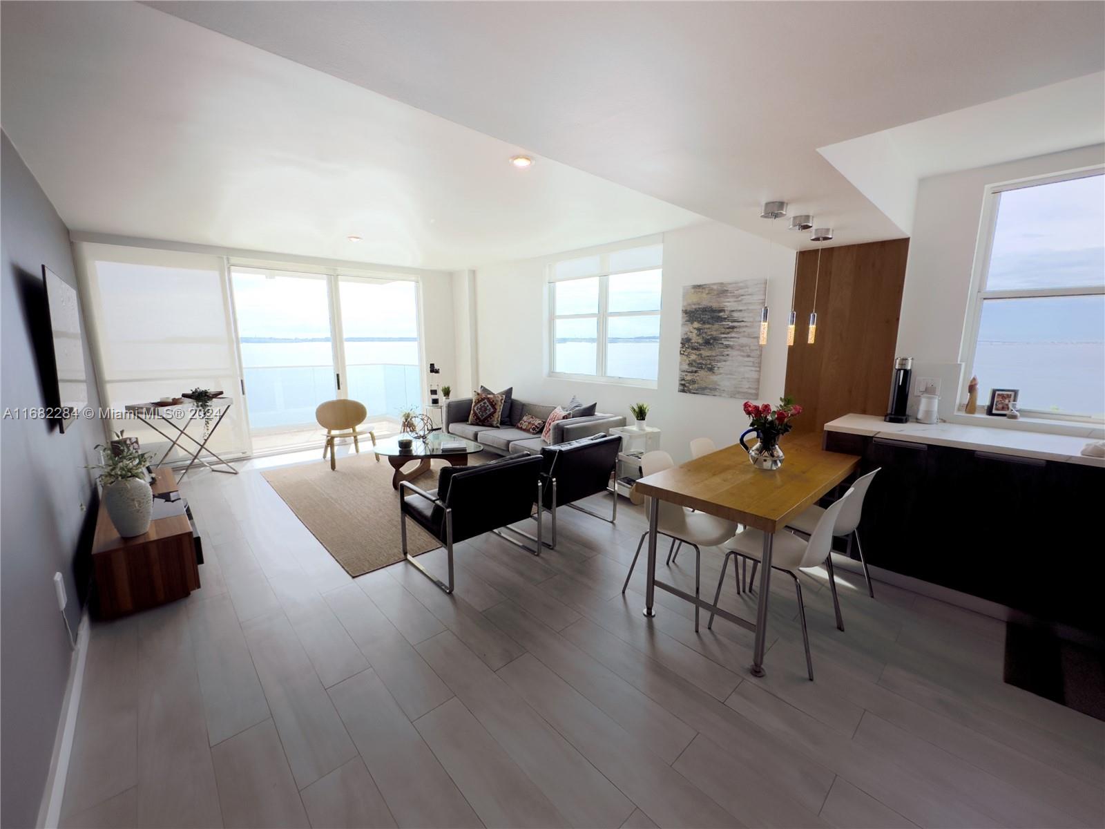 a living room with furniture a large window and wooden floor