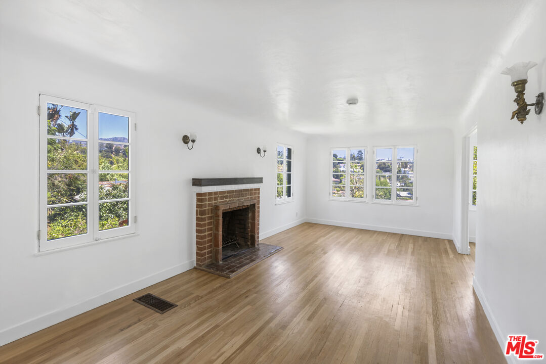 an empty room with windows and fireplace