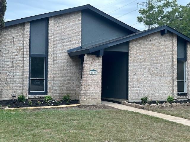 a brick house with a yard and large parking space