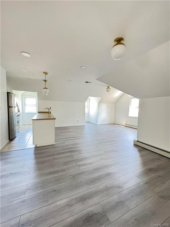 Bonus room with a baseboard heating unit, a wealth of natural light, sink, and light hardwood / wood-style floors