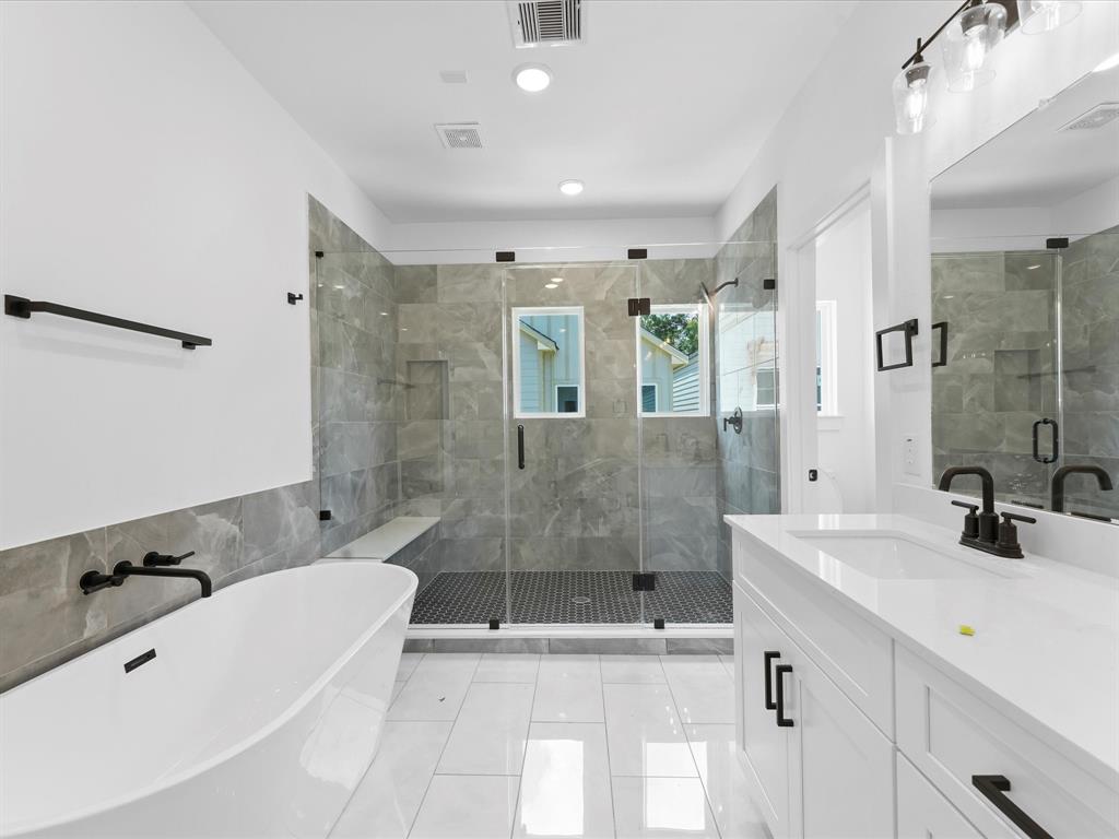 a bathroom with a bathtub shower sink mirror and toilet