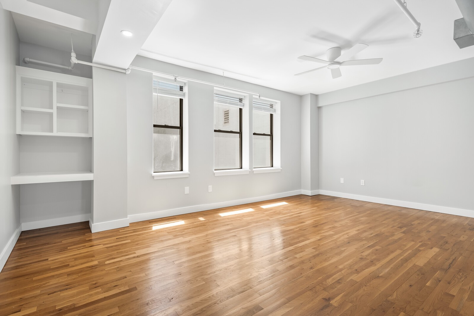 an empty room with wooden floor and windows