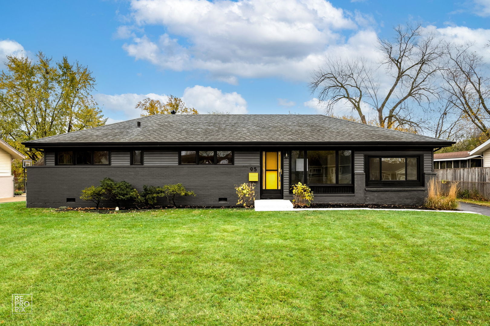 a view of a brick house with a big yard and large trees